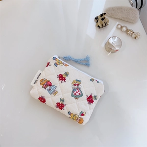 Close-up of quilted floral cosmetic bag with cartoon print and simple wish label