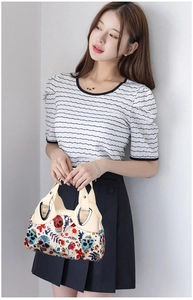 Detailed shot of floral skull print handbag with silver heart-shaped metallic buckle