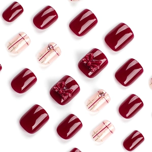 Elegant deep red and beige press-on nails with golden glitter, bows and rhinestones