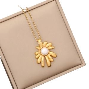 Elegant gold flower necklace with pearl pendant in a beige jewelry display box