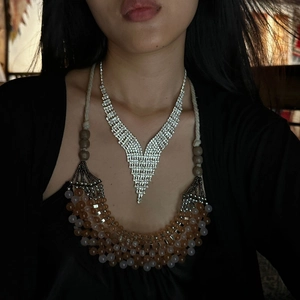 Close-up of V-shaped diamond necklace and colorful beaded layers on an elegant model