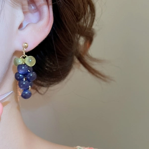 Macro detail of grape-shaped drop earrings with purple beads and golden accents