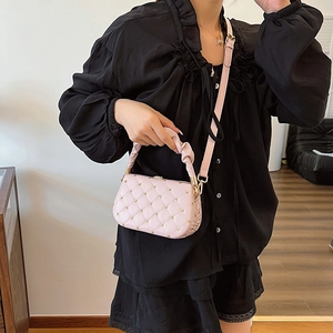 Pink quilted crossbody bag with heart charm and ruffled handle worn by a model