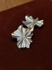 Detailed view of silver ruffled petal earrings with a metallic irregular floral design