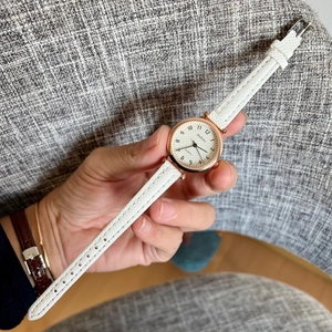 Close-up of white leather quartz watch with rose gold case and checkered dial