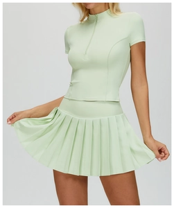 Dettaglio del top fitness verde menta con mezza zip e gonna a pieghe in tessuto elastico