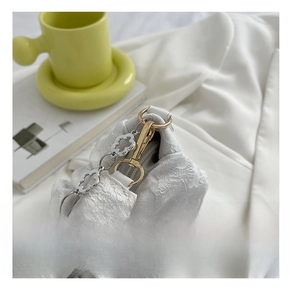 Detail of white pleated handbag featuring silver floral chain and gold hardware