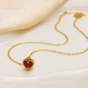 Elegante collana a catena dorata con ciondolo a cuore rosso su sfondo di seta