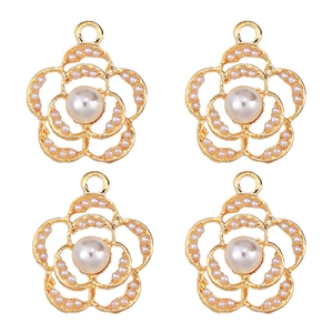 Detailed view of four golden flower pendants with inlaid pearls and zircons for jewelry making