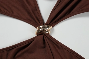 Detail of deep brown dress featuring a gold metal twist ring and ruched fabric texture