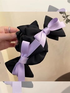 Close-up of elegant large double-layered purple and black bow claw clip in hand