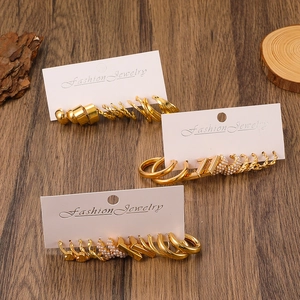 Detailed view of assorted gold-tone pearl and rhinestone earrings set on wood