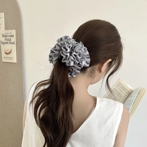 Detail of grey satin oversized scrunchie styled on a ponytail in a chic French setting