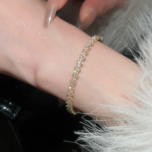Detailed view of luxury gold bangle with sparkling heart and rectangle zircons on wrist