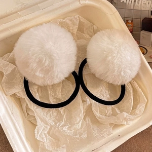 Close-up of white faux fur pom-pom hair ties in a gift box with a soft aesthetic