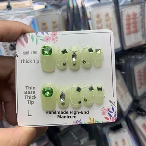 Détail de faux ongles vert clair avec strass, perles et pointes épaisses en taille L