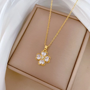 Detail of clover pendant with heart-shaped clear zircons on gold chain and silk