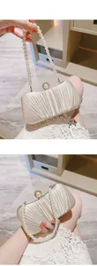Detail of elegant pleated satin evening clutch with pearl handle and clasp