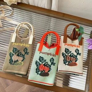 Close-up of three knitted mini handbags featuring pumpkin patterns on a glass table