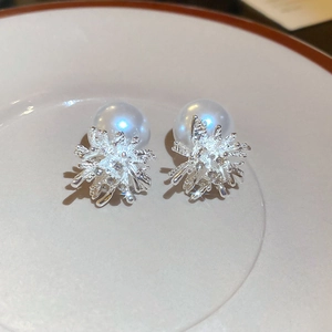 Macro shot of silver fireworks pearl earrings on white ceramic plate, detailed metalwork