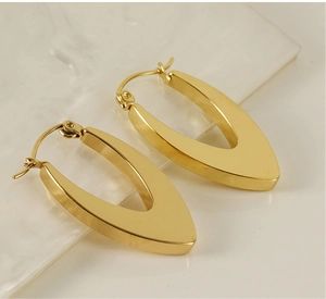 Detailed view of gold V-shaped stainless steel earrings on a white marble surface