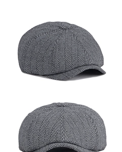 Detail view of newsboy cap with classic black and grey herringbone pattern and top button