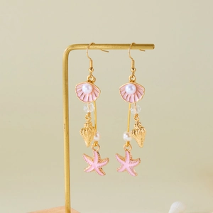 Detail view of long tassel earrings with pink shells, sea stars and white imitation pearls
