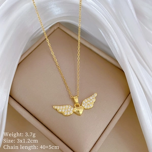 Detail of gold heart necklace with crystal wings on white silk, 3x1.2cm pendant size