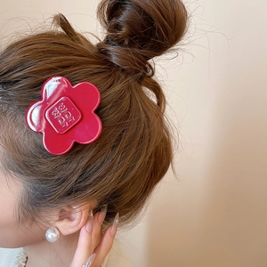 Detail of red resin flower hair clip with letter embossing on a model hair