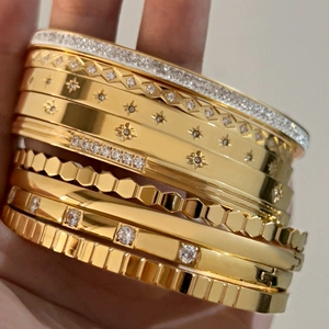 Detail of gold-plated stainless steel bangles with honeycomb and star pattern textures