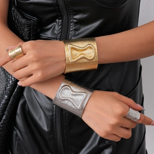 Wide open cuff bracelet with vertical texture and raised hourglass motif in gold and silver