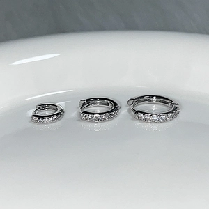 Three sizes of silver pavé hoop earrings with sparkling zircons on white ceramic