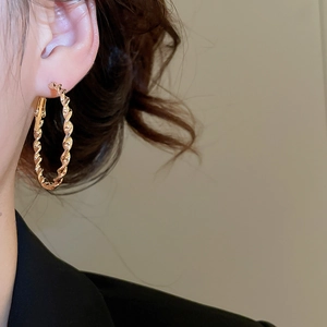 Nahaufnahme goldener gedrehter Creolen mit Spiralstruktur und Metallglanz-Finish