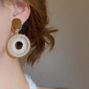 Detailed side view of Bohemian woven hoop earrings with brown resin on female model