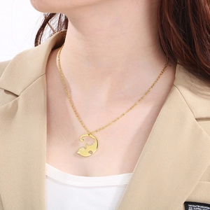 Détail d'un collier avec pendentif chat doré porté par un mannequin en blazer beige