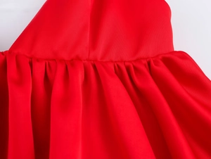 Vue détaillée du tissu satiné rouge montrant les fronces délicates et les coutures de qualité
