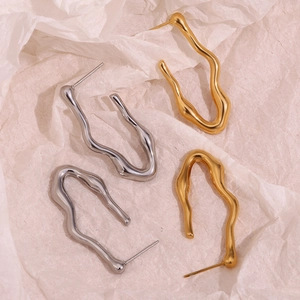 18K gold plated and silver stainless steel wave V-shaped hoop earrings on beige paper