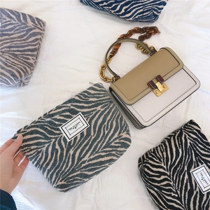 Close-up of zebra pattern canvas bags and a chic leather bag with amber chain