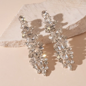Macro detail of rhinestone tassel earrings with crystal droplets on textured stone