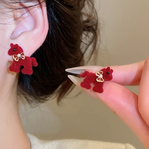 Detail of red flocked puppy earrings with golden bow and pearl accent on ear