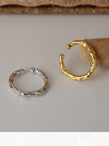 Detailed macro view of gold and silver hammered texture metal ear cuffs on a wooden stand