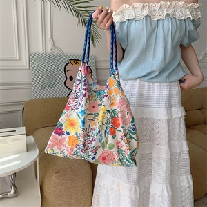 Detail of floral tote bag showing colorful canvas texture and sturdy blue woven rope handle