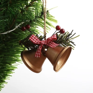 Detail of Christmas iron bells with red berries, pine needles, and a checkered bow