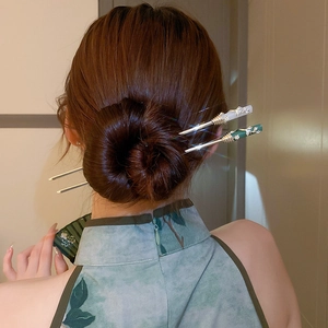 Détail d'épingles à cheveux fleurs style chinois blanc et vert sur un chignon élégant