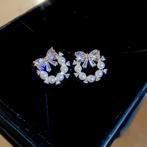 Macro shot of bowknot pearl earrings with sparkling rhinestones in a black velvet jewelry box