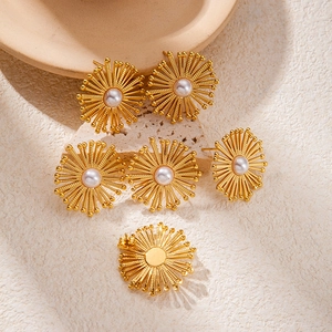 Elegant gold plated sunflower pearl earrings with central white pearl on cream background