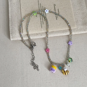 Detail of beaded necklace featuring crystal beads with colorful flower and honey bee charms