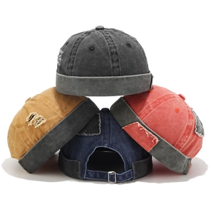 Detailed pile of four distressed docker caps in charcoal, yellow, navy, and red canvas