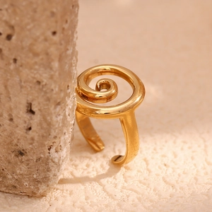 Detailed view of an 18K gold plated stainless steel spiral ring on a textured stone
