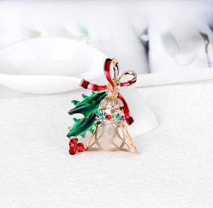 Detailed view of an elegant Christmas bell brooch featuring a red bow and green holly